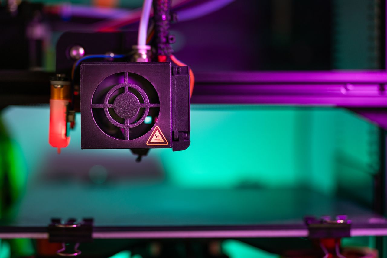 Vibrant close-up of a 3D printer component in action with colorful lighting creating a modern industrial vibe.